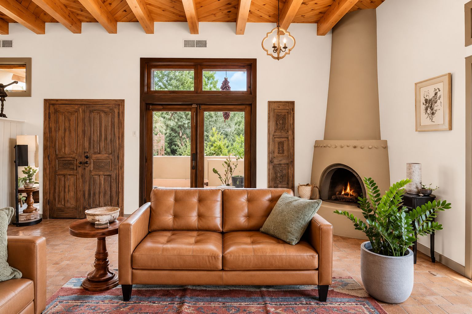 A cozy living room with a leather sofa, a fireplace, and a large window overlooking greenery.