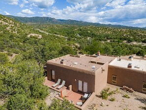 Un bâtiment moderne doté d’un toit plat, entouré d’un paysage désertique à la végétation clairsemée et dominé par des montagnes lointaines.