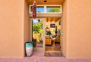 A doorway leading to a living area with a sofa, a lamp, and a cactus on a shelf. - Quiet Luxury Retreat, Mtn Views, Walk to Four Seasons, 3 Patios, Hiking galore! (Santa Fe)