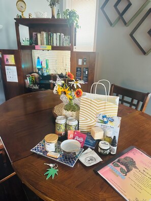 A wooden dining table with a vase of flowers, a striped bag, and various items including cans, a jar, and a keychain. - Serene 2-bedroom apartment with concierge in vibrant St. Louis (St. Louis)