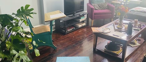 A living room with a television, a sofa, a coffee table, and a large plant.