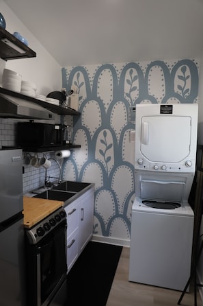 A compact kitchen with a stove, oven, microwave, and a washing machine. - The Skylight Studio- A Hidden Gem (Atlanta)