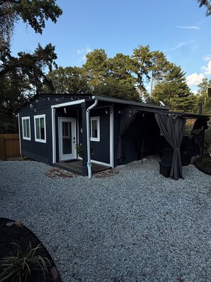 A small, two-story building with a gravel driveway, a covered porch, and a door with a small step leading up to it. - The Skylight Studio- A Hidden Gem (Atlanta)