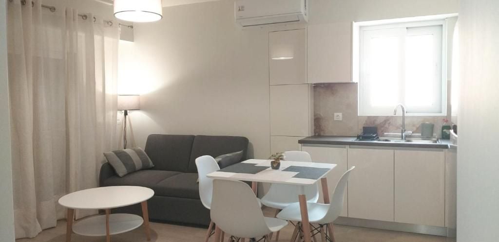 A compact living space with a kitchenette, a dining area with a table and chairs, a sofa, and a lamp.