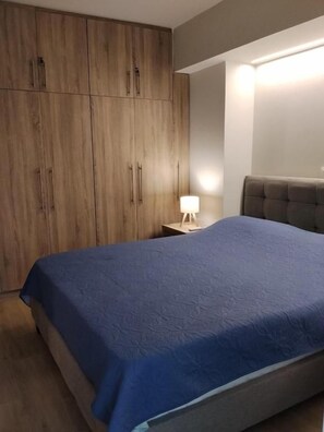 A bedroom with a bed, a nightstand, a lamp, and a wardrobe. - Helios House - New Build - 2bedrooms & Parking (Metamorfosi)