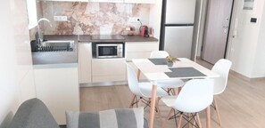 Eine moderne Küche mit Einbauofen, Mikrowelle und einer kleinen Essecke mit Tisch und Stühlen.