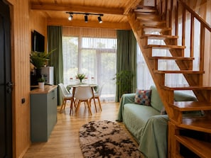 A wooden interior with a staircase, a dining area with a table and chairs, and a sofa. - Cottage Buknari (Diviti)
