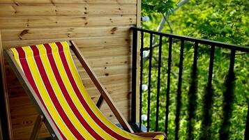 Une terrasse en bois avec un seul fauteuil de jardin à rayures.