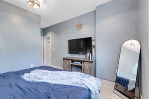 A bedroom with a bed, a television, a mirror, and a dresser. - Manzil Suite | Cozy 2BR Private Retreat (Maple Ridge)