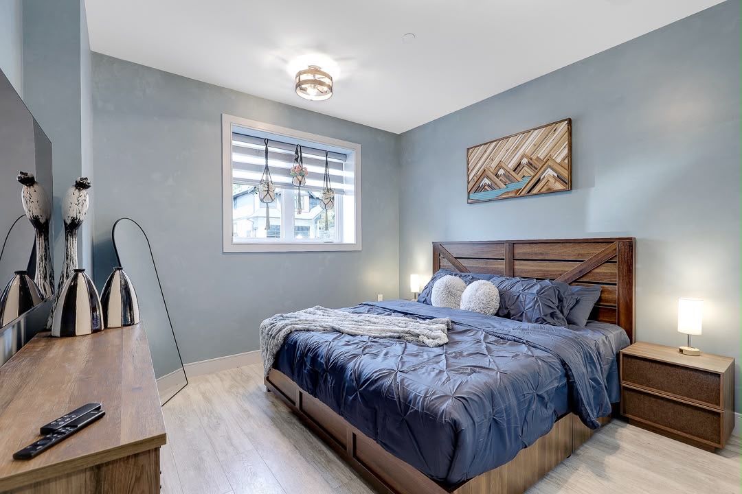 A bedroom with a bed, bedside tables, a window with blinds, and wall art.