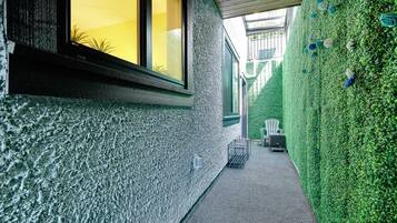 A narrow pathway flanked by a textured wall and a hedge with decorative elements.