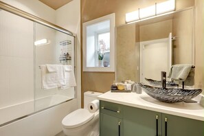 A modern bathroom with a glass shower enclosure, a toilet, a sink with a unique bowl-shaped basin, and a mirror with a window above it. - Manzil Suite | Cozy 2BR Private Retreat (Maple Ridge)