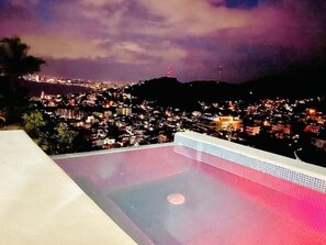 A rooftop pool with a city view at night. - Casa Zoe (Puerto Vallarta)