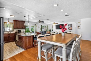 A spacious kitchen with wooden cabinets, a central island, and a dining area with a wooden table and chairs. - Heated Pool + Game Room, Near Clearwater Beach (Largo)