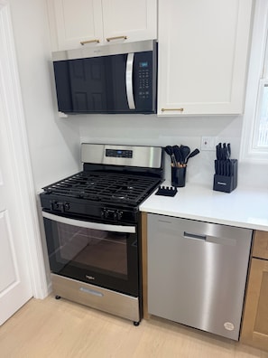 A kitchen with a stainless steel dishwasher, a black stove, and a microwave above the stove. - NEW LISTING! Escape to the Cape Beach Retreat (Cape May)