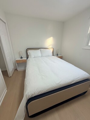 Une chambre à coucher avec un lit, des tables de chevet et une fenêtre.