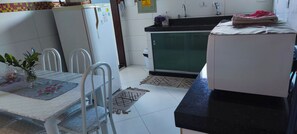 Cozinha com mesa, cadeiras, geladeira, pia e fogão.