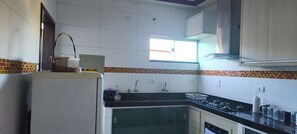 Una cocina con armarios blancos, encimera negra y ventana que deja entrar luz natural.