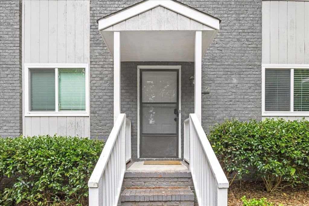 A residential building with a front porch, a door, and a staircase leading to the entrance.