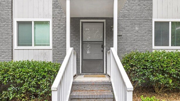 Un immeuble résidentiel doté d’un porche à l’avant, d’une porte et d’un escalier menant à l’entrée.