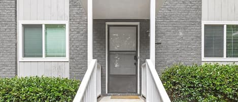 A residential building with a front porch, a door, and a staircase leading to the entrance.
