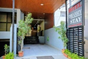 The entrance to a hotel with a sign reading 'HOTEL THE COZY STAY' and a staircase leading inside. - Deluxe Room the Cozy Stay (Indore)