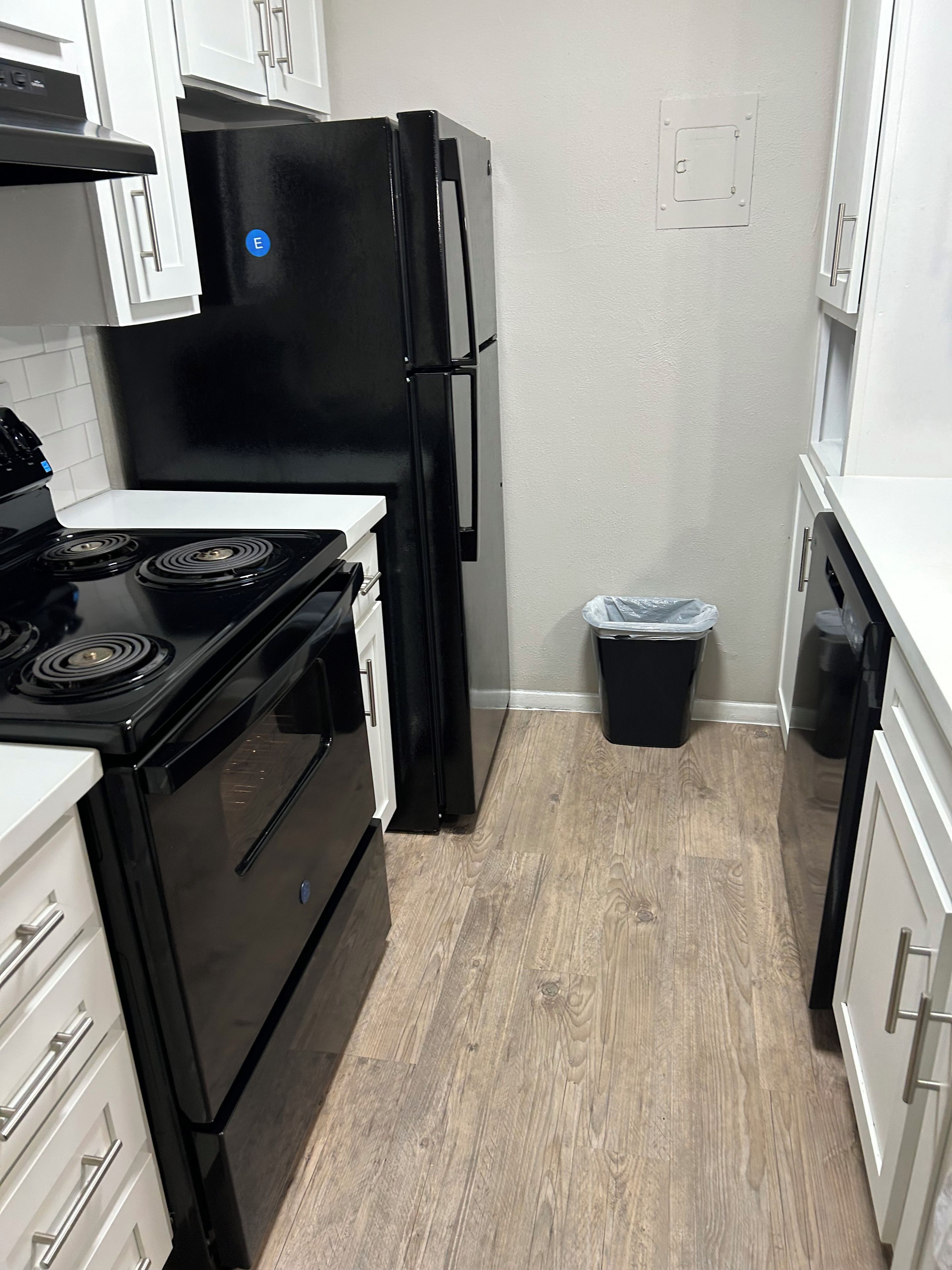 A compact kitchen with a black refrigerator, white cabinets, and a stainless steel stove.