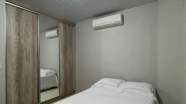 Une chambre à coucher comprenant un lit, une armoire et un appareil de climatisation.