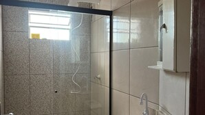 Une salle de bain avec douche, toilettes et lavabo.