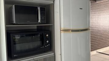 Eine Küche mit einem weißen Kühlschrank, einer schwarzen Mikrowelle und einem schwarzen Backofen.