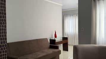 Ein modernes Wohnzimmer mit einem braunen Sofa, einem Glastisch und einer roten Vase.