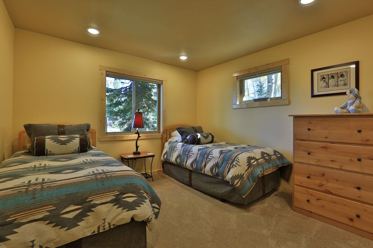 A bedroom with two beds, a dresser, and a window.