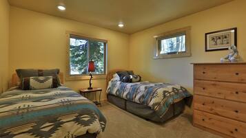 A bedroom with two beds, a dresser, and a window.