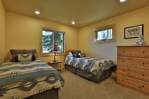 A bedroom with two beds, a dresser, and a window. - The Aspen Cabin (West Yellowstone)