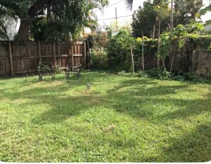 A grassy yard with a wooden fence, trees, and a small structure. - Cozy 1-bedroom Casita in the heart of Miami (Miami)