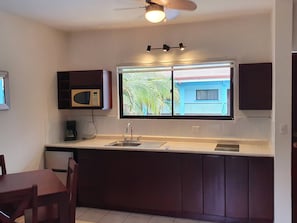 Una cocina con ventana, microondas y ventilador de techo.
