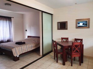 A hotel room with a bed, a dining table with chairs, a TV, and a sliding door. - Marina Loft Studio Number 223 (Sardinal)