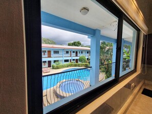 Habitación de hotel con vista a una piscina y un edificio con varios balcones.