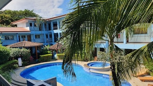 A swimming pool with a surrounding deck, palm trees, and a building with balconies in the background. - Marina Loft Studio Number 223 (Sardinal)