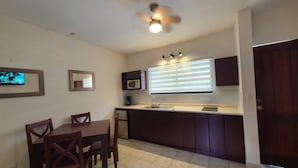 A compact kitchen with a dining table, chairs, a microwave, and a ceiling fan. - Marina Loft Studio Number 223 (Sardinal)