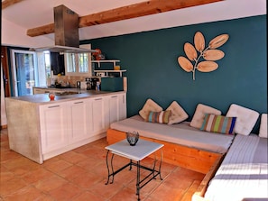 A compact kitchen with white cabinets, a central island, and a dining area with a bench and table.