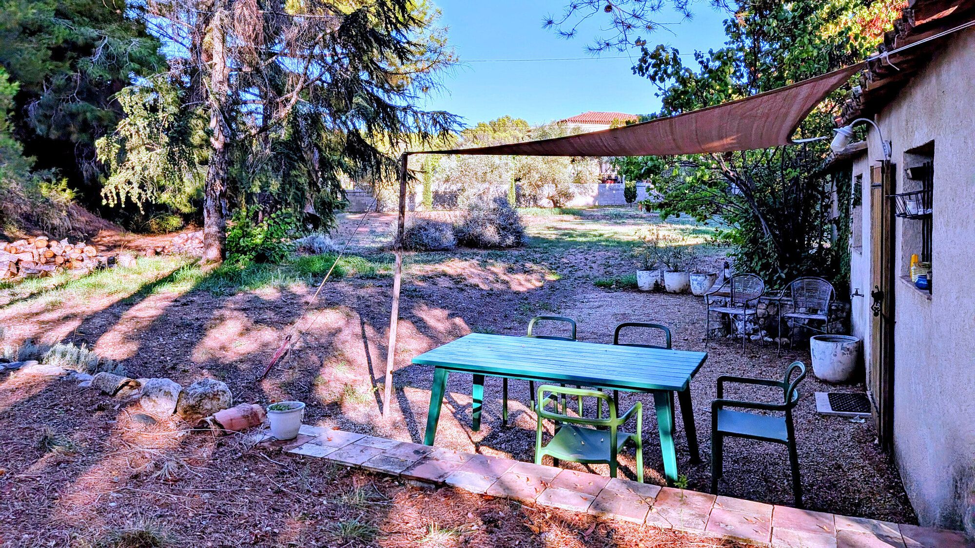 A patio with a table and chairs, surrounded by trees and a building.