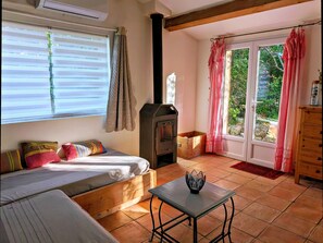 A cozy room with a bed, a table, a fireplace, and a view of greenery outside.
