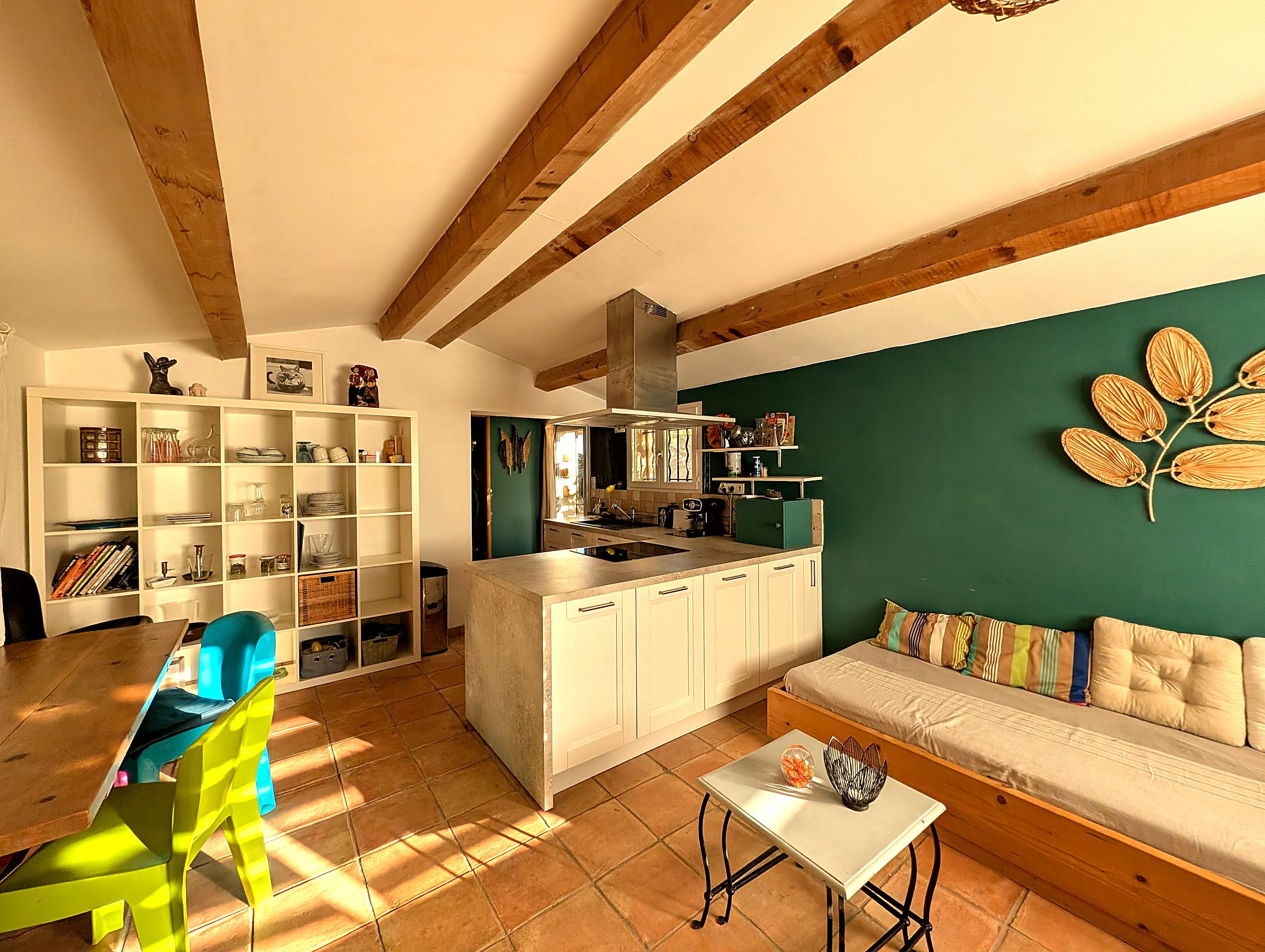 Une cuisine moderne avec des meubles blancs, un mur d’accent vert et un plafond en bois.