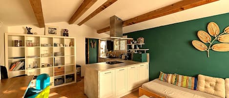 A modern kitchen with white cabinets, a green accent wall, and a wooden ceiling.