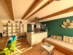 A modern kitchen with white cabinets, a green accent wall, and a wooden ceiling.