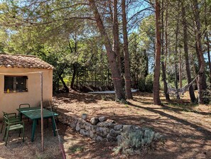 A rustic cabin with a stone wall and a small table and chair set outside. - Small stone house with a pool and pine forest – 10 minutes from Aix-en-Provence (Aix-en-Provence)