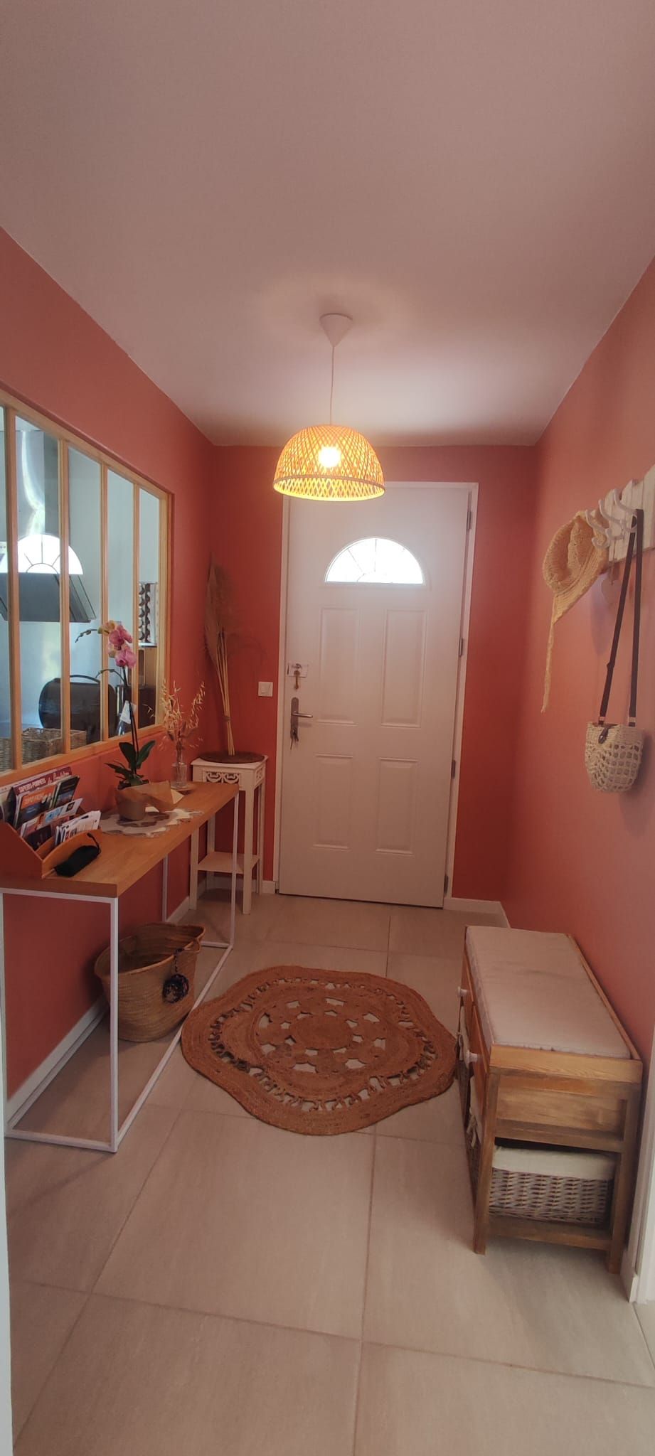 A hallway with a wooden bench, a woven rug, a hanging light fixture, and a door.