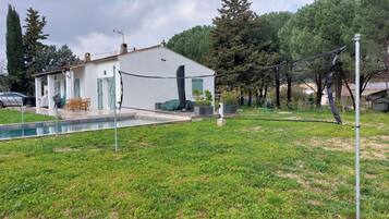 Une maison avec une piscine, un court de tennis et une cour clôturée.