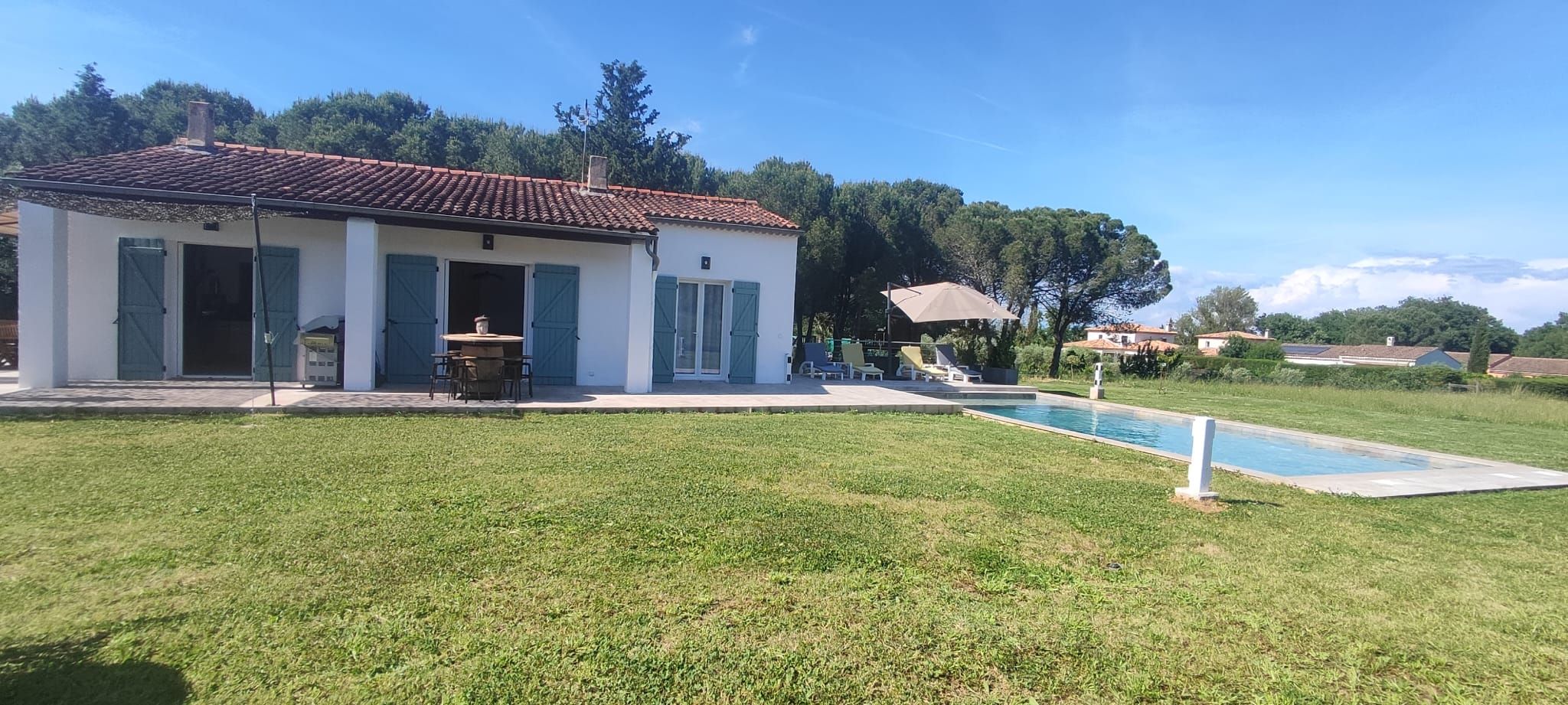 Une maison avec une piscine, une terrasse dotée de mobilier d’extérieur et une pelouse.